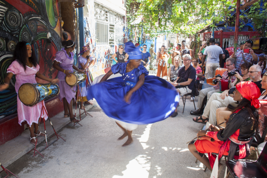In Cuba, if there's music playing, there's almost never a wrong time to dance. Salsa Dancing in Cuba: Women in colorful dresses play instruments and dance in front of a crowd on a sunny day.