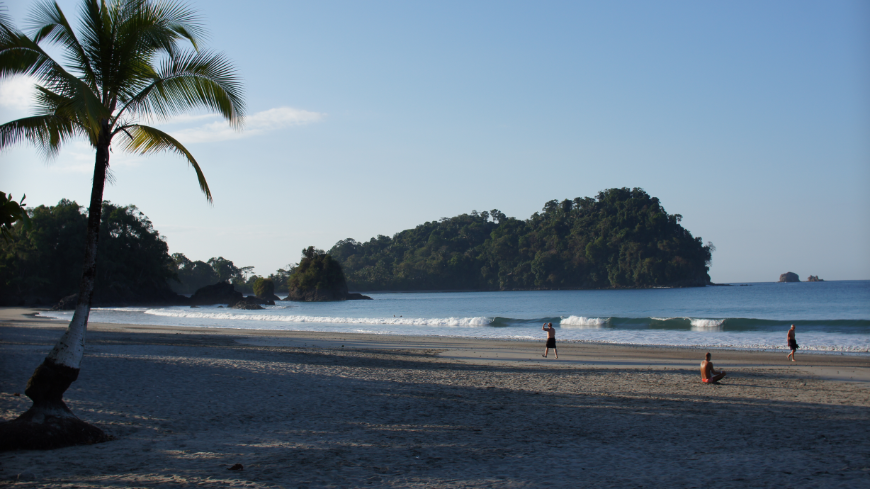 Sustainability Image: A beach scene shows three people enjoying the Sun, sand, and waves. 