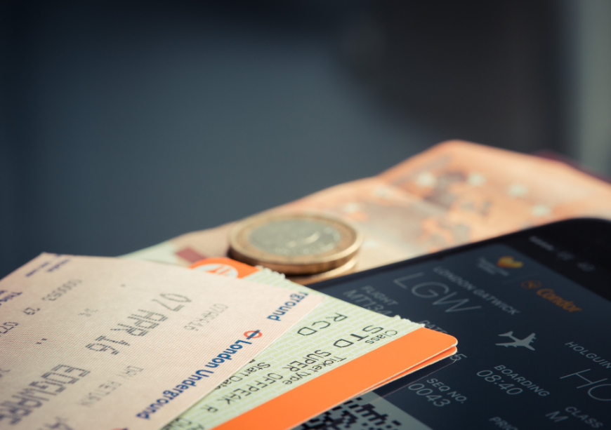 International travel isn't like an impromptu road trip—planning in advance is a must. Tropical Holiday Image: Travel tickets laying on a table, with a coin currency or token on top of them.