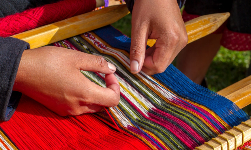 Like your memories of your holiday in Peru, this textile isn't mass-produced—it's one of a kind. Peruvian Souvenirs Image: Hands skillfully craft a textile on a loom.