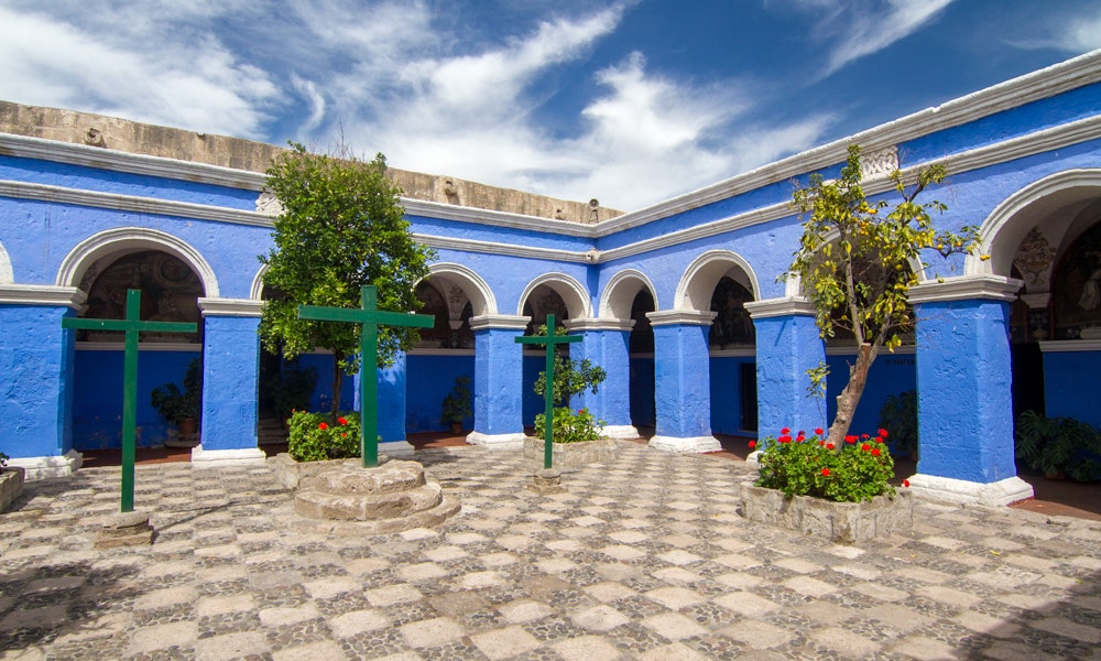 What's bluer, the sky or the building? Unique Peru Image: The courtyard of a bright blue building is filled with tile, green crosses, and vibrant flowers.