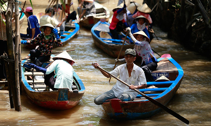 This commute beats sitting in bumper-to-bumper traffic any day! Vietnam Island Destinations Image: Locals paddle their boats in the water as they go about their daily lives.