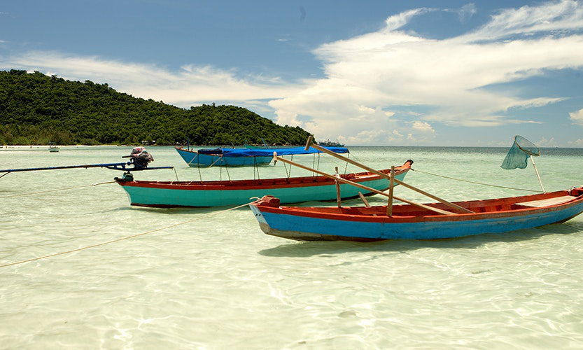 Feel up to taking a boat out, or would you rather splash around the shoreline? Vietnam Island Destination Image: Two long and colorful boats have been pulled up to the shore.