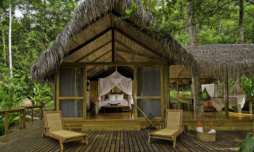 Even indulging at an ecolodge is supporting stewards of the environment. You can't escape sustainability in Costa Rica ;-) Why Is Costa Rica The Happiest Country Image: An ecolodge with a thatched roof has a bedroom which opens up to an outdoor space.