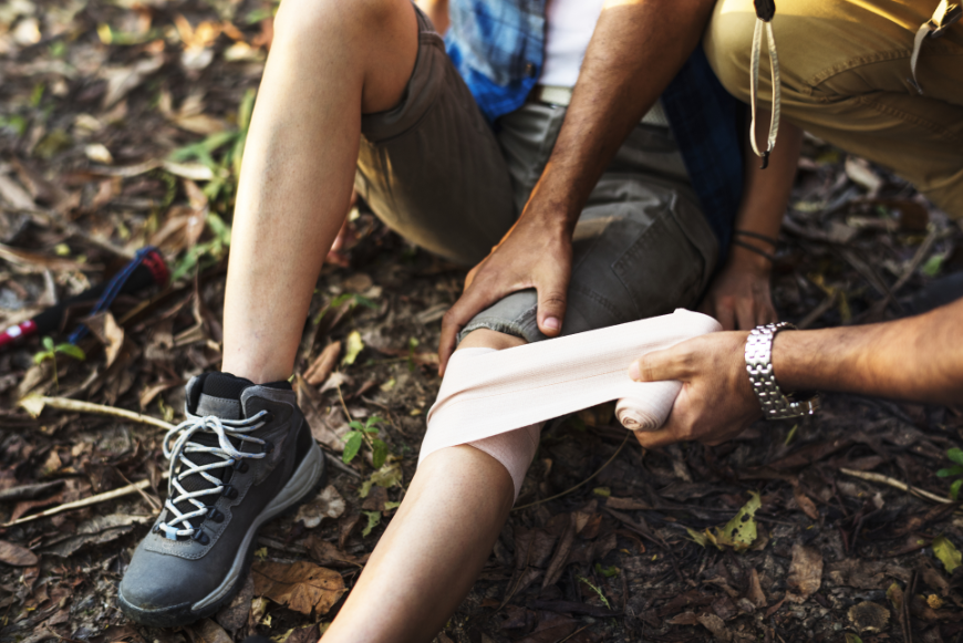 A minor injury doesn't have to ruin your vacation or cost you a fortune--IF you have traveler's insurance. Why Travel Insurance Is A Must Image: An injured hiker gets their leg bandaged.