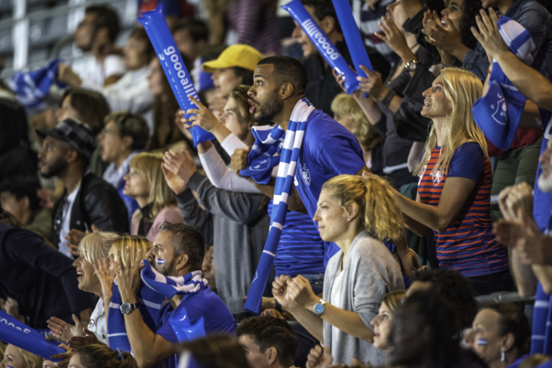 A crowd wears blue and cheers on their team.